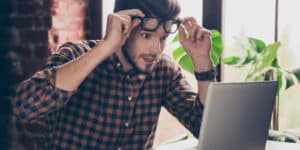 Young shocked surprised man in glasses looking on laptop.