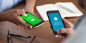 Two people's hands, holding phones, one sending money and one receiving money via a cash app