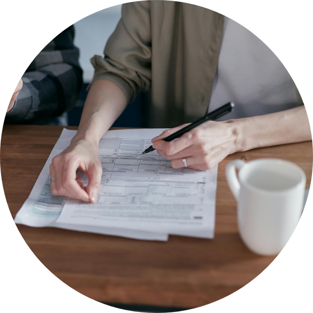 Person filling out tax form with pen.