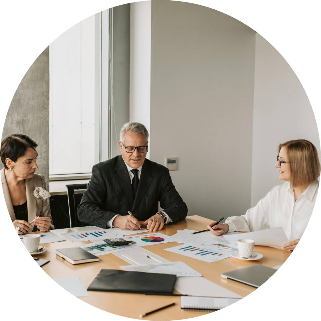 Three business professionals analyze charts at a conference table.