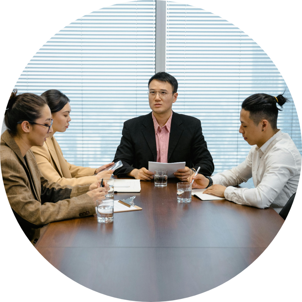Professional business team of four colleagues discussing financial documents during corporate boardroom meeting around conference table