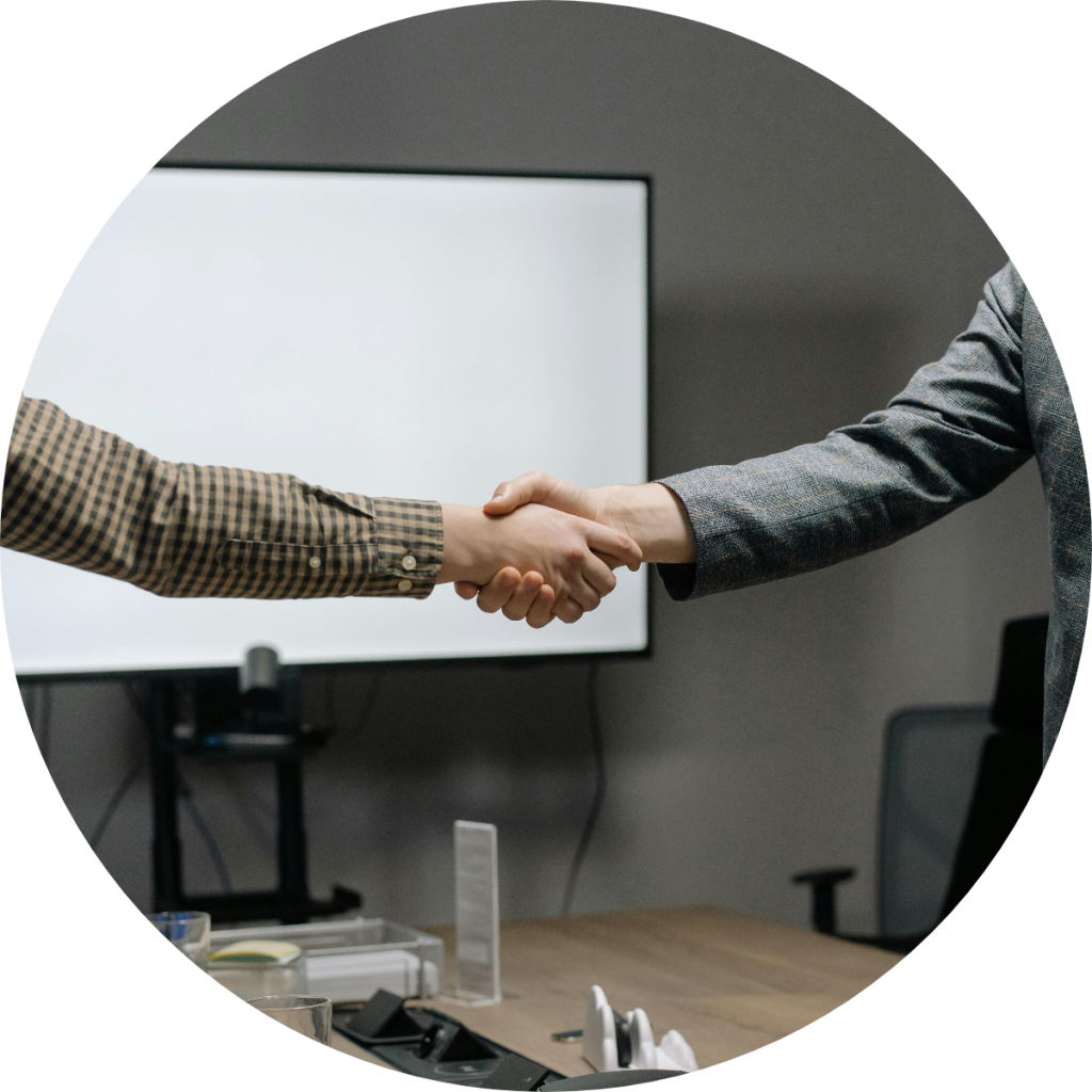 Two business professionals shaking hands in corporate conference room after successful financial agreement, partnership deal, or client consultation meeting