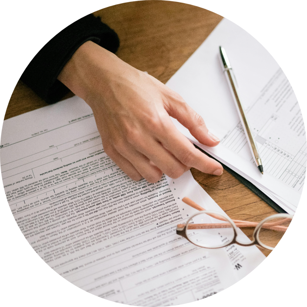 Person reviewing IRS Form 4506-T and W-2 tax documents on wooden desk with glasses and pen during federal tax return preparation or audit process