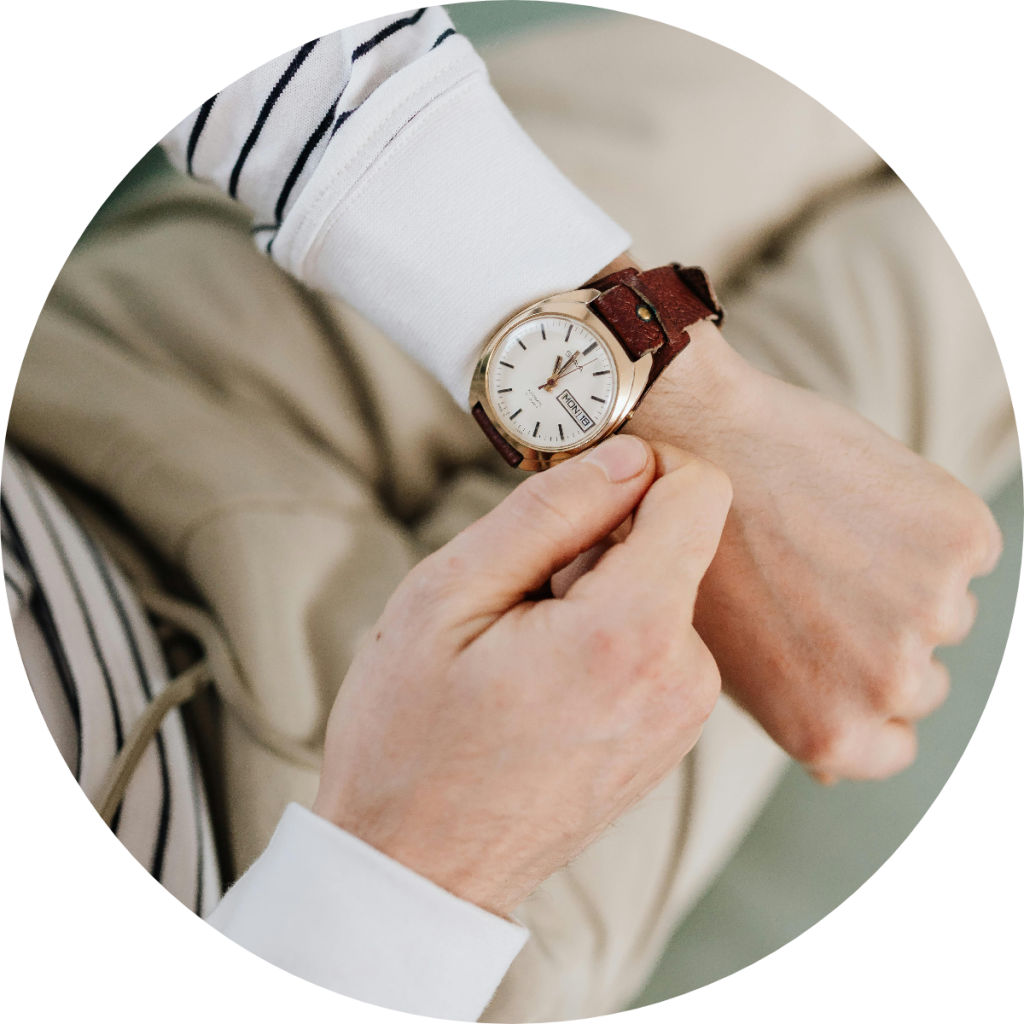 Business professional adjusting gold analog wristwatch with brown leather strap, concept of tax deadline countdown, financial appointment punctuality, or time management