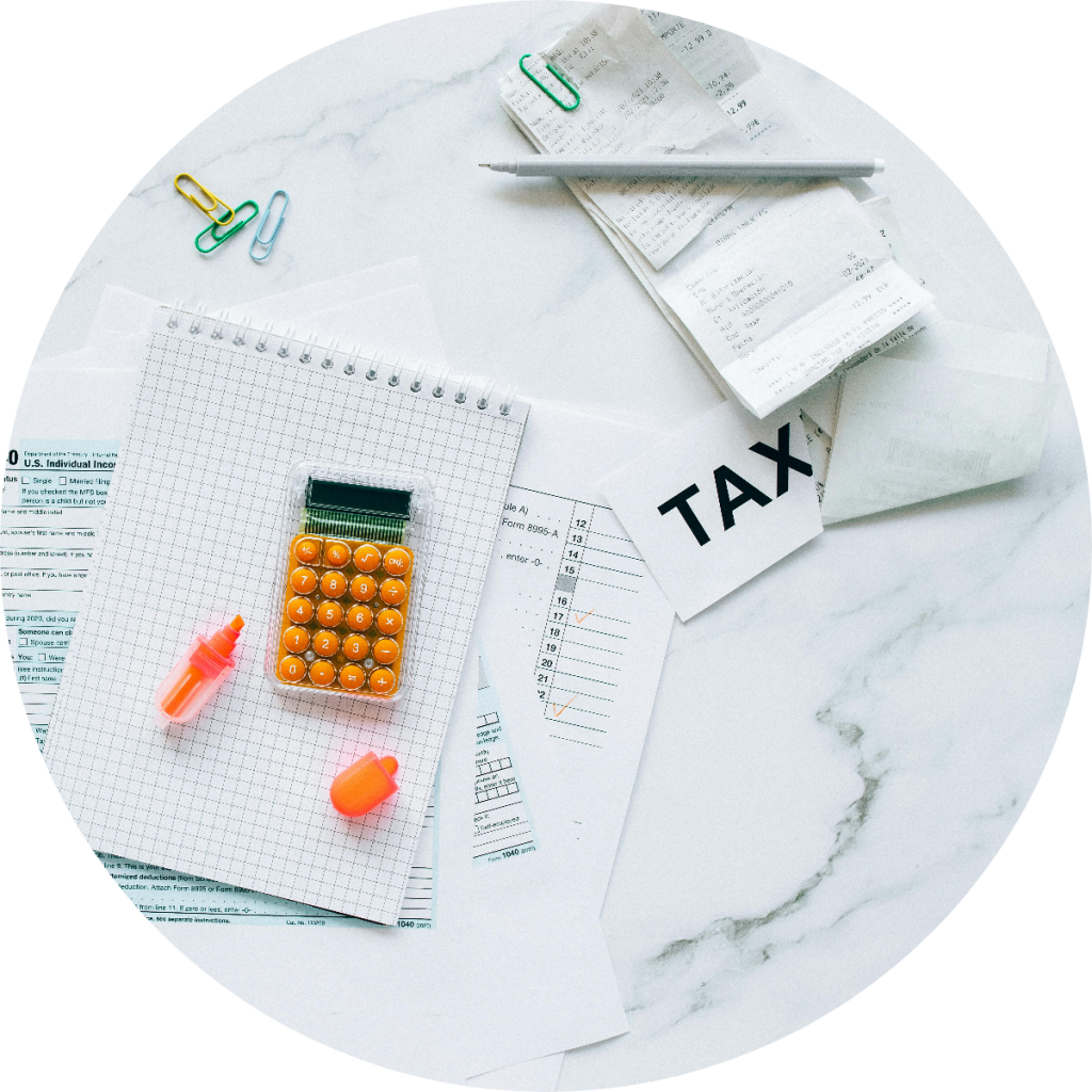 Tax preparation flat lay with IRS Form 1040, orange calculator, pink highlighter, receipts, and TAX label card on marble surface for small business annual tax filing
