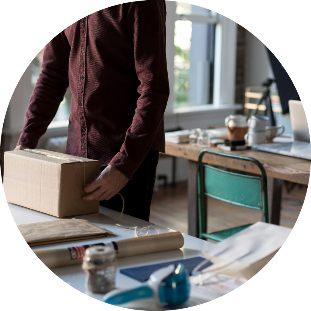 Small business owner packaging cardboard box for shipment in home office workspace, concept of ecommerce small business tax deductions and self-employment income reporting