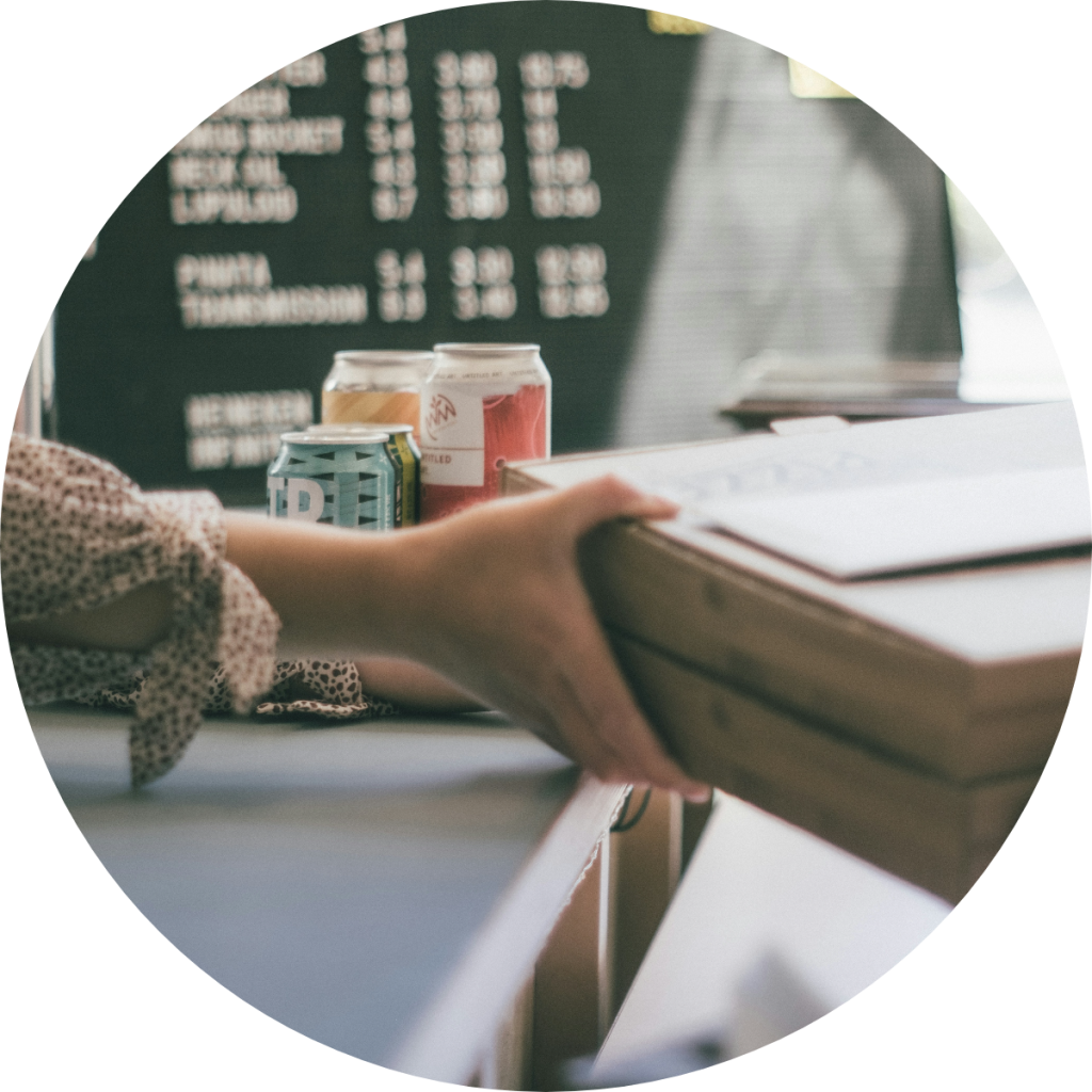 Customer receiving menu or bill at craft beer bar counter with canned beverages and chalkboard price list, small business hospitality and point-of-sale transaction concept