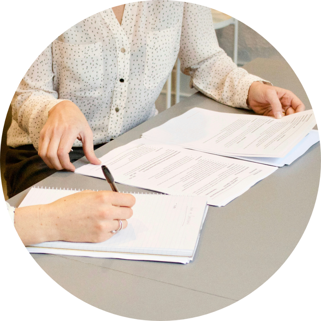 Tax advisor or accountant reviewing and pointing to financial documents and legal paperwork with client across desk during tax consultation or business accounting services meeting